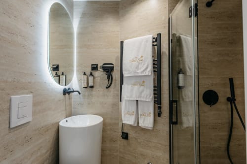 Banheiro moderno na villa Vila Ouro em Villas Eden com paredes em travertino, espelho oval iluminado, toalheiro e chuveiro tipo chuva