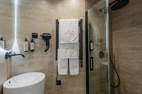Banheiro moderno na vila Villas Eden com paredes de travertino, toalheiro branco, chuveiro tipo chuva e comodidades de luxo