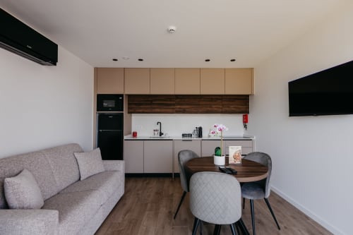 Cozinha moderna integrada e sala de estar na Vila Rubi do Villas Eden, com sofá cinzento, mesa de jantar e totalmente equipada
