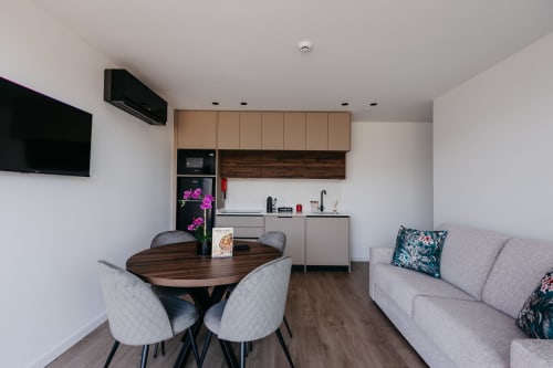 Cozinha e sala de estar modernas na Villas Eden com mesa de jantar, sofá cinza e kitchenette equipada