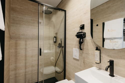 Banheiro moderno na villa Vila Onix em Villas Eden com paredes de travertino, box de vidro e acabamentos pretos