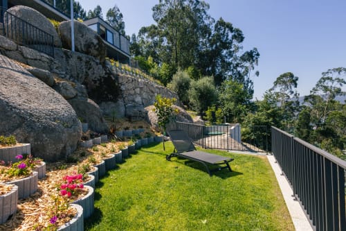 Terraço luxuoso em Villas Eden com jardim bem cuidado, espreguiçadeira, flores rosa, rochas gigantes e vista para as montanhas