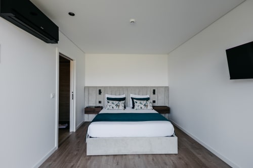 Quarto moderno na Vila Quartz, villa Villas Eden com cama queen, roupa de cama verde-azulado e TV de tela plana