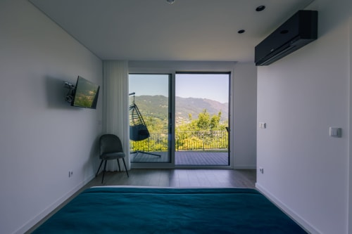 Suíte moderna na Villas Eden com vista para as montanhas através de portas de vidro, parede com detalhe escuro e mobiliário contemporâneo