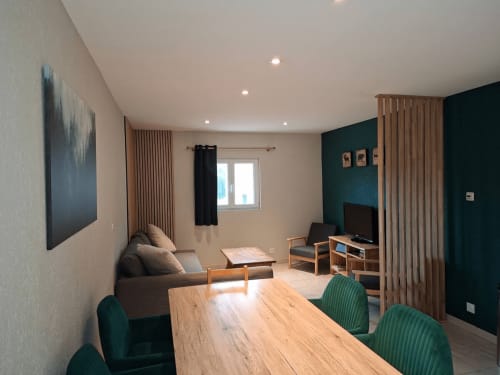 Espace de vie et salle à manger contemporains aux Trois Marches B&B à Lamoura, avec mur accent bleu-vert et mobilier en bois