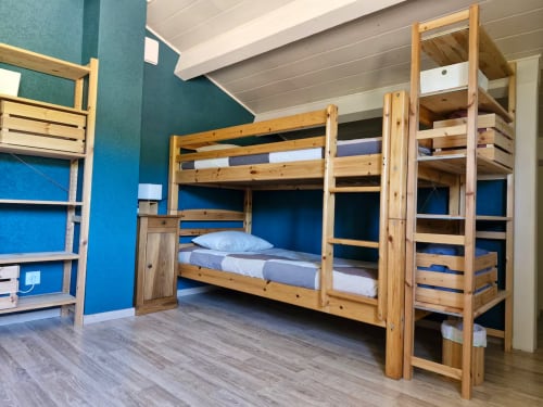 Chambre dortoir de l'auberge Les 3 Marches à Lamoura avec lits superposés en bois, murs bleus et étagères de rangement