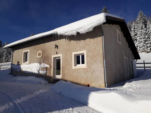 Vue hivernale enneigée du chalet Les 3 Marches B&B à Lamoura, France, toit couvert de neige et glaçons