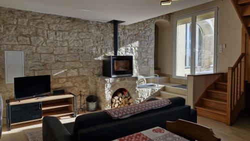 Salon moderne des 3 Marches B&B à Lamoura avec cheminée, canapé noir et escalier en bois
