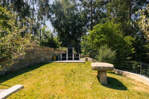 Área de estar ao ar livre na Villas Eden com estruturas de pedra, gramado verde e árvores ao redor em Portugal