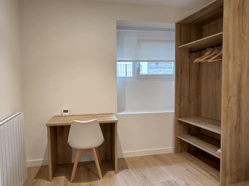 Espacio de trabajo moderno en habitación de hotel MTM Rooms con escritorio de madera, silla, armario integrado y ventana con vista a la ciudad