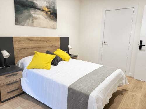 Habitación doble moderna del hotel MTM Rooms en Santander con almohadas amarillas, cabecero de madera y decoración contemporánea