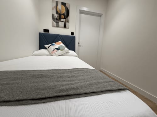 Habitación individual limpia en el hotel MTM Rooms de Santander con cabecero azul marino, ropa de cama blanca y obras de arte moderno