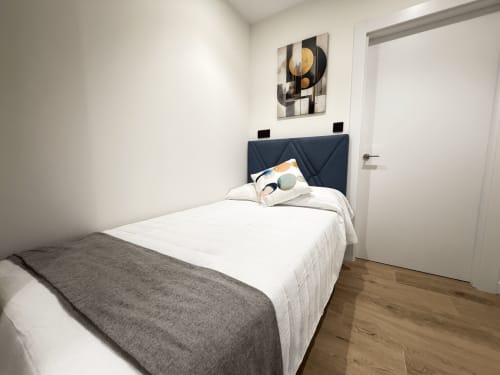 Habitación individual del hotel MTM Rooms en Santander con ropa de cama blanca, cabecero oscuro y arte abstracto moderno en la pared
