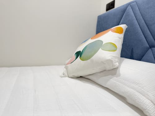 Almohada decorativa con diseño acuarela abstracto en ropa de cama blanca de habitación individual del hotel MTM Rooms Santander
