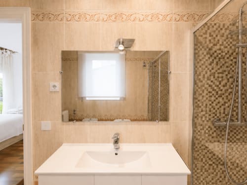 Baño moderno en la casita Alborada, Baiona con espejo grande, lavabo blanco, paredes alicatadas y ducha de cristal