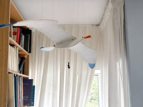 Dormitorio de cabaña costera con móvil de gaviota blanca y estantería de madera en casa con vistas al mar de Baiona