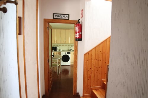 Pasillo de cocina en Hostal Rosa - Nonna en Sigüenza con puertas de madera, extintor e electrodomésticos visibles