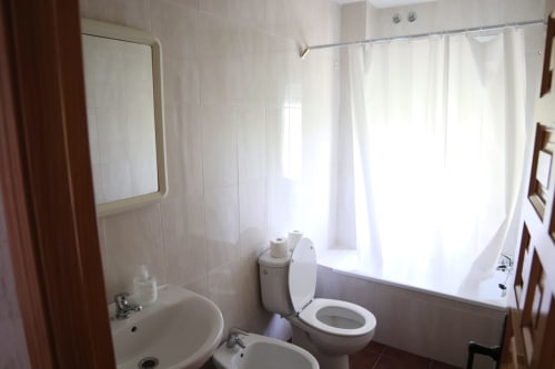 Baño limpio en Hostal Rosa - Nonna de Sigüenza con inodoro, lavamanos, espejo y cortina de ducha