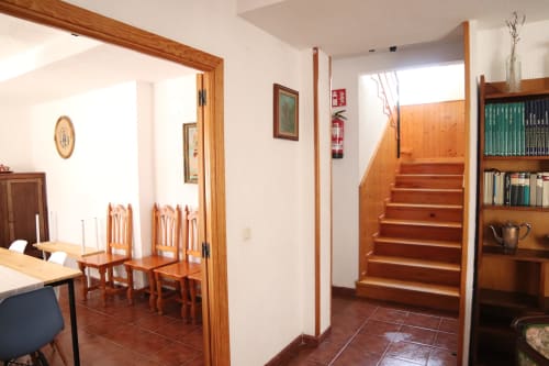 Hostal Rosa - Entrada de Nonna en Sigüenza con escaleras de madera, zona de comedor, estantería y decoración tradicional