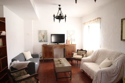 Luminosa sala de estar del Hostal Rosa - Nonna en Sigüenza con cómodos asientos, TV, muebles de madera y decoración clásica