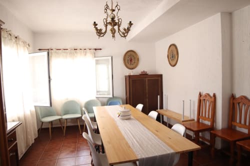 Comedor del Hostal Rosa - Nonna en Sigüenza con mesa de madera, sillas, araña y decoración vintage