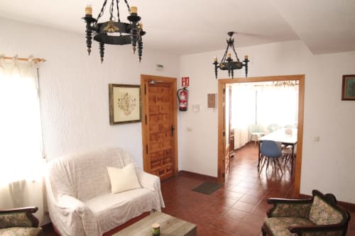 Hostal Rosa - Sala común Nonna en Sigüenza con sillón blanco, puertas de madera y candelabros decorativos