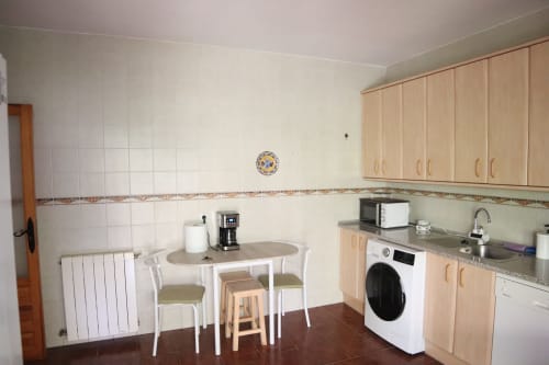 Cocina Nonna del Hostal Rosa en Sigüenza con mesa de comedor, muebles de madera, lavadora y electrodomésticos