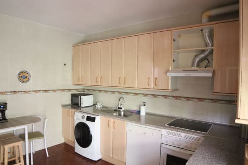 Cocina moderna en Hostal Rosa - Nonna de Sigüenza con muebles de madera, electrodomésticos de acero inoxidable y encimeras de azulejos