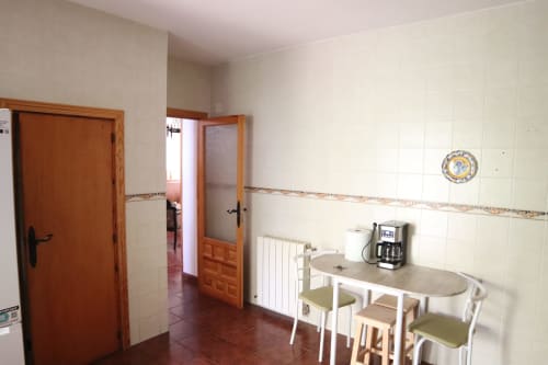 Zona común de cocina en Hostal Rosa-Nonna en Sigüenza con mesa de comedor, cafetera y puertas de madera