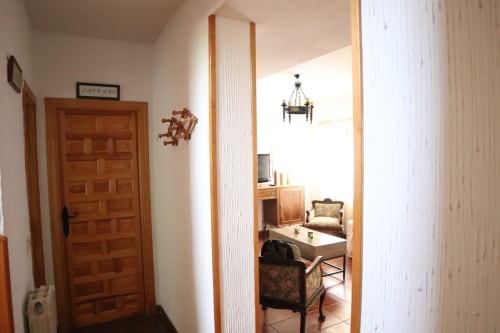 Entrada del pasillo del Hostal Rosa - Nonna en Sigüenza, con acceso a dormitorio de puerta de madera y mobiliario visible