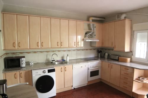 Cocina del Hostal Rosa - Nonna en Sigüenza con muebles de madera, encimeras de granito y electrodomésticos modernos