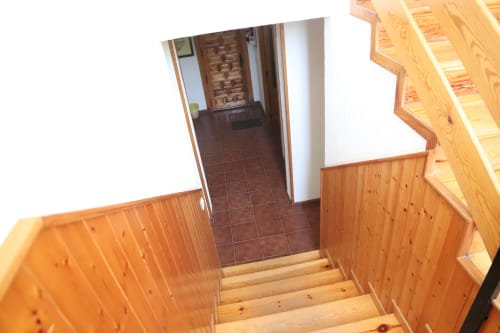 Escalera de madera en Hostal Rosa - Nonna, Sigüenza, con pasillo de baldosas marrones