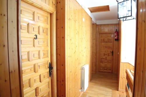 Pasillo de madera en el Hostal Rosa-Nonna de Sigüenza con puerta número 3, radiador y claraboya