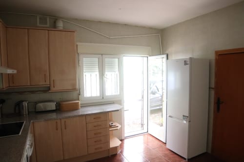 Cocina luminosa del Hostal Rosa-Nonna en Sigüenza con muebles de madera, electrodomésticos blancos y puertas correderas al patio