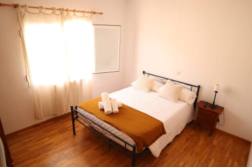 Habitación luminosa en Hostal Rosa - Nonna en Sigüenza con cama doble, suelo de madera y luz natural por ventana con cortinas