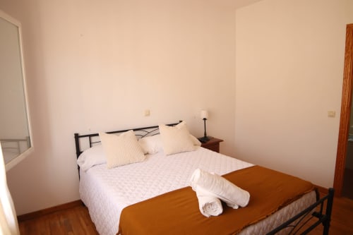 Acogedora habitación en Hostal Rosa - Nonna de Sigüenza con cama doble, mesita de noche de madera y ropa de cama blanca