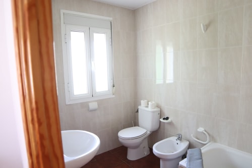Luminoso baño del Hostal Rosa - Nonna en Sigüenza con sanitarios blancos, bidé, inodoro y bañera