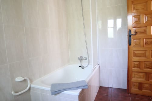 Baño del Hostal Rosa - Nonna en Sigüenza con bañera, mampara de ducha cristal y puerta de madera