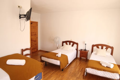 Hostal Rosa - Habitación dormitorio Nonna en Sigüenza con tres camas, muebles de madera y ventilador.