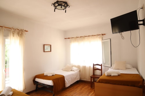 Habitación doble en Hostal Rosa - Nonna de Sigüenza con camas de madera, sábanas blancas y TV en la pared