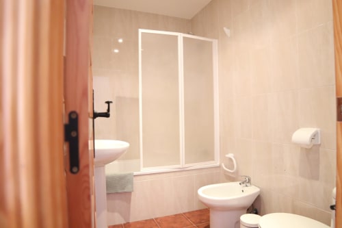 Baño moderno del Hostal Rosa-Nonna en Sigüenza con mampara de ducha, lavabo e inodoro