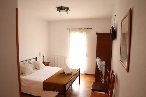 Habitación luminosa del Hostal Rosa-Nonna en Sigüenza con cama, armario y luz natural desde las puertas