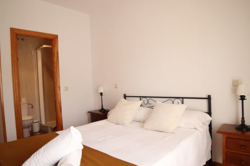 Habitación en Hostal Rosa - Nonna de Sigüenza con cama de hierro forjado, ropa blanca y baño privado