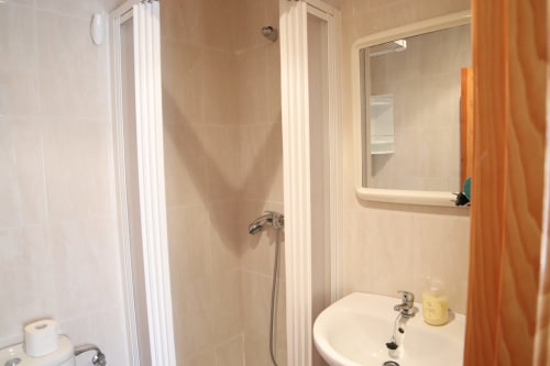 Baño del Hostal Rosa - Nonna en Sigüenza con ducha, lavabo, espejo y cortina naranja