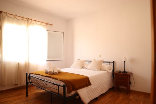 Luminosa habitación en el Hostal Rosa - Nonna de Sigüenza con suelos de madera, cama de hierro y cálida luz natural