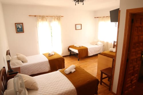 Hostal Rosa - Habitación triple Nonna en Sigüenza con tres camas, muebles de madera y luz natural desde las ventanas