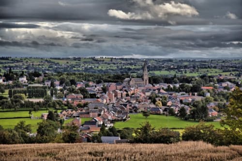 Aerial view of Mortroux Dalhem village with church spire, green fields, and red-roofed buildings in Belgium