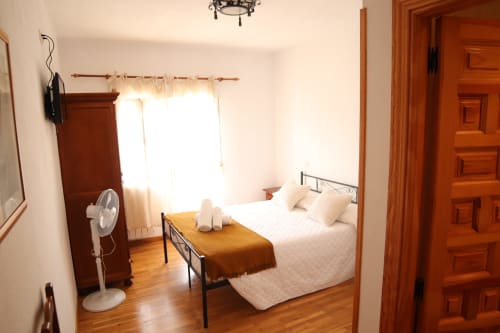 Luminosa habitación de hostal en Hostal Rosa - Nonna en Sigüenza con cama de madera, sábanas blancas y luz natural de la ventana