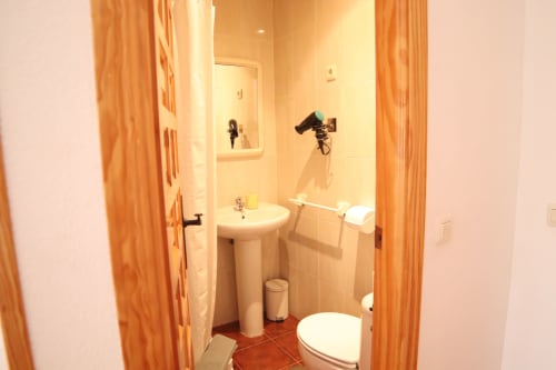 Baño compacto en Hostal Rosa-Nonna de Sigüenza con lavabo pedestal, inodoro y ducha