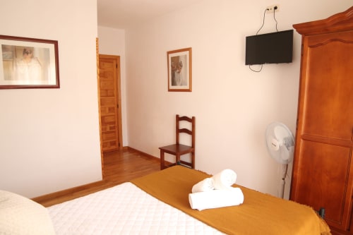 Hostal Rosa - Habitación Nonna en Sigüenza con cama, muebles de madera, TV y ventilador